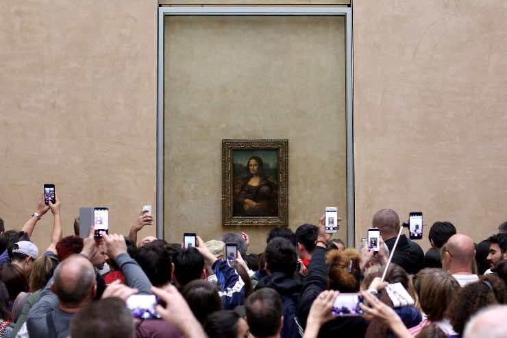 muchas personas haciendo fotos a la Gioconda ejemplo de overtourism